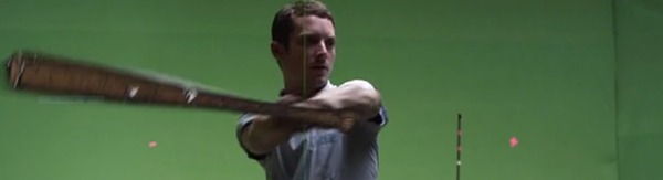 Man swinging a baseball bat in front of a green screen